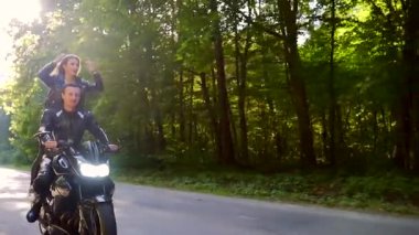  Genç çift ormanda motosiklet sürüyor.