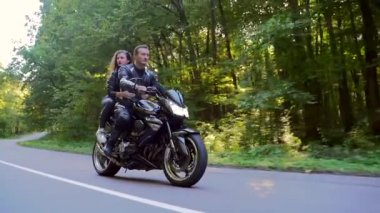  Genç çift ormanda motosiklet sürüyor.