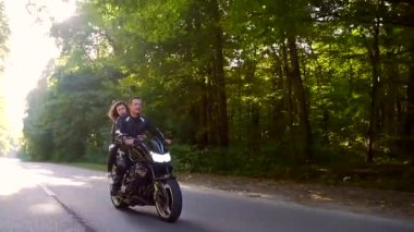  Genç çift ormanda motosiklet sürüyor.