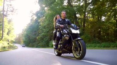  Genç çift ormanda motosiklet sürüyor.