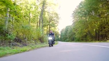  Genç çift ormanda motosiklet sürüyor.