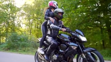  Genç çift ormanda motosiklet sürüyor.