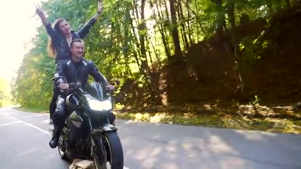 Молода пара їде на мотоциклі на лісовій дорозі — стокове відео