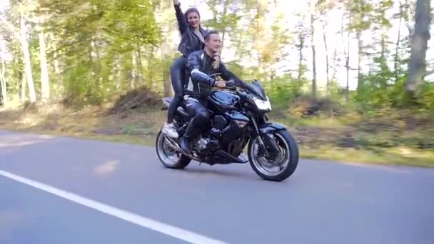 Pareja joven monta una motocicleta en un camino forestal — Vídeos de Stock