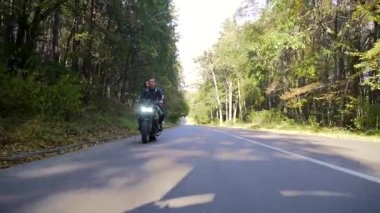  Genç çift ormanda motosiklet sürüyor.