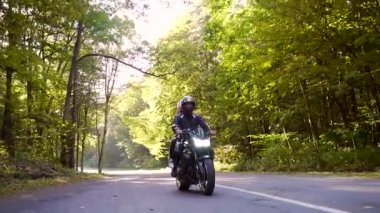  Genç çift ormanda motosiklet sürüyor.