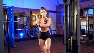 Kaslı vücudu olan, kırmızı etekli bluz giyen, siyah şortlu spor kulübünde poz veren ve kameraya bakan kendine güvenen bir kadın. Vücut geliştirme ve günlük aktivite kavramı.