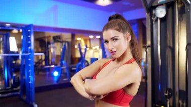 Kaslı vücudu olan, kırmızı etekli bluz giyen, siyah şortlu spor kulübünde poz veren ve kameraya bakan kendine güvenen bir kadın. Vücut geliştirme ve günlük aktivite kavramı.