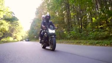  Genç çift ormanda motosiklet sürüyor.