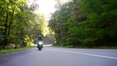  Genç çift ormanda motosiklet sürüyor.