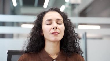 Genç iş kadını iş yerinde çalışırken derin bir nefes alıp veriyor. Gülümseyen mutlu bayan çalışan gözleri kapalı dinleniyor. Neşeli kadın işe ara verdi. Kapat.