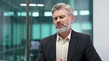 Modern bir iş yerinde çalışırken öksüren hasta, olgun bir işadamı. Soğuk algınlığı ya da resmi kıyafetli grip çalışanı kendini kötü hisseder, kendini kötü hisseder ve elini göğsüne bastırır. Kapat.