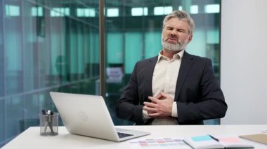 Sağlıksız, olgun iş adamı iş yerinde mide ağrısını hisseder. Resmi kıyafetli hasta işçinin mide ekşimesi, mide iltihabı ya da zehirlenmesi var. Erkek, spazm ya da kabızlıktan muzdarip.