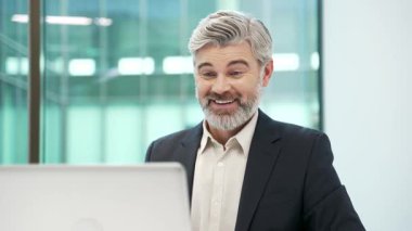 Memnun iş adamı iş yerindeki iş yerinde otururken dizüstü bilgisayarından harika haberler aldı. Resmi takım elbiseli, mutlu erkek girişimci bilgisayarda olumlu bir mesaj okuyor. Kapat.