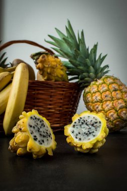 Ağaçtan bir yüzey üzerinde pitaya, muz ve ananas gibi farklı sarı meyvelerin yaşamı