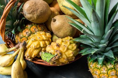 Ağaçtan bir yüzey üzerinde pitaya, muz ve ananas gibi farklı sarı meyvelerin yaşamı