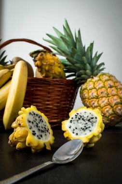 Ağaçtan bir yüzey üzerinde pitaya, muz ve ananas gibi farklı sarı meyvelerin yaşamı