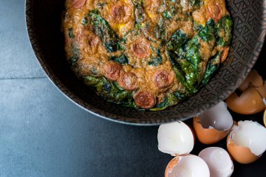 Bir tencerede ıspanaklı kek, ahşap bir masada yumurta kabukları.