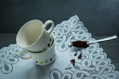 İki kahve fincanı ve masa örtüsünde kahve olan bir kaşık. 