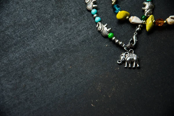 Siyah ahşap bir yüzey üzerinde bazı fillerin renkli gümüş bileziği