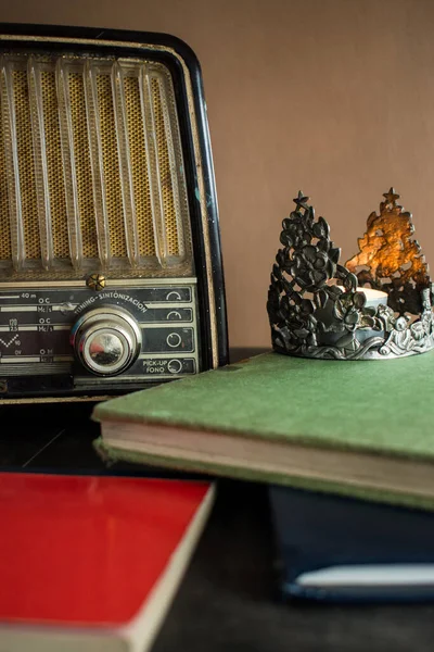 Eski bir radyo, birkaç defter ve siyah ahşap bir masada bir mum. 