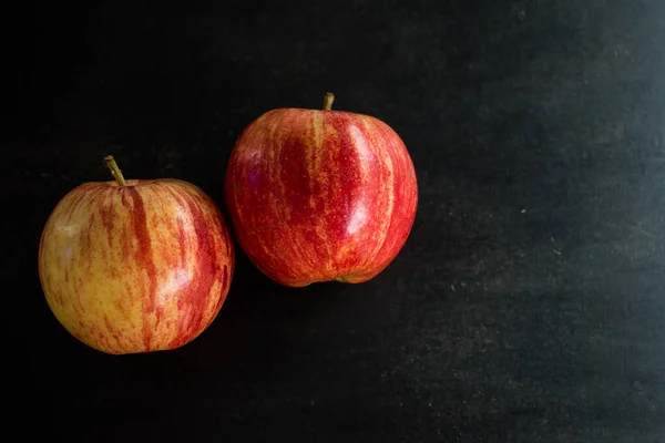 Taze kırmızı ve sarı elmalar siyah tahta bir masada.  