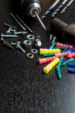 Matkap gibi hırdavatçı aletleri ve siyah ahşap bir masa üzerindeki cıvatalar.  