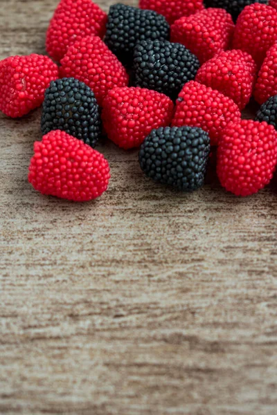 木制表面上甜甜的黑莓红色和黑色橡胶 — 图库照片