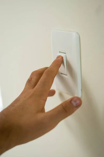 Latin el beyaz bir duvara beyaz bir düğmeye basıyor. 