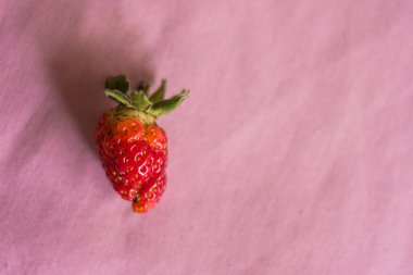 Eski pembe masa örtüsünün üzerinde taze kırmızı çilek