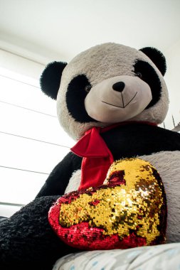 Doldurulmuş kırmızı ve altın bir kalbi olan büyük bir panda.