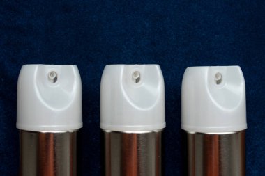 Renkli bir masada beyaz kapaklı metal aerosol kutuları. 