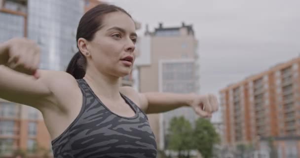 Nahaufnahme einer Sportlerin in grauer Uniform, die intensiv trainiert, hinter ihr in einem Hochhaus sitzt, ein Konzept für einen gesunden Lebensstil in der Stadt — Stockvideo