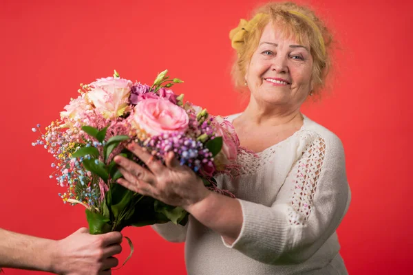 Yaşlı bir kadına bir buket lale veren genç bir kadının elleri. 8 Mart, anneler günü konsepti.