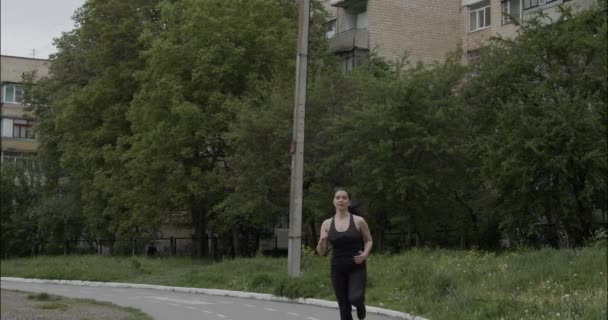 Menina atlética com cabelo escuro em um traje cinza em um maidanchik esportes corre, vídeo em câmera lenta — Vídeo de Stock