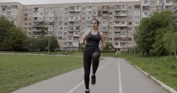 Menina atlética em um uniforme de esportes cinza está treinando, corre no local e leva seus joelhos alto, conceito de um estilo de vida saudável — Vídeo de Stock