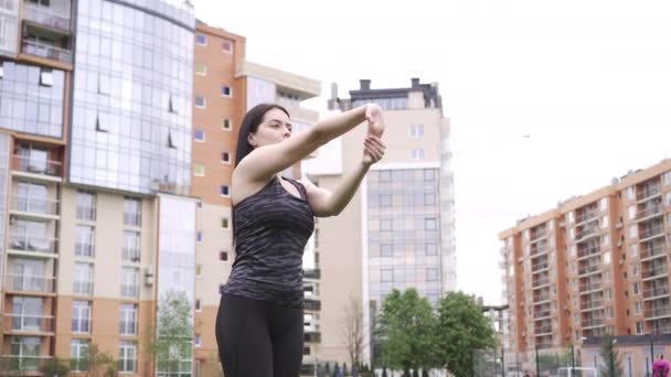 En sportbyggd flicka i grå uniform gör en intensiv träning, sitta i hennes lägenhet byggnad, ett koncept för en hälsosam livsstil i staden — Stockvideo