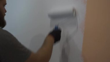 Adam salgın zamanında evde duvar boyuyor. Beyaz boya. Kapat.