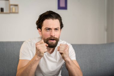 Bir adam evdeki bir kanepede tek başına oturur ve futbol maçını seyreder. Duygusaldır. Gördüklerine tepki verir..