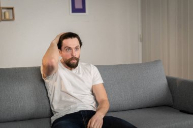 Bir adam evdeki bir kanepede tek başına oturur ve futbol maçını seyreder. Duygusaldır. Gördüklerine tepki verir..