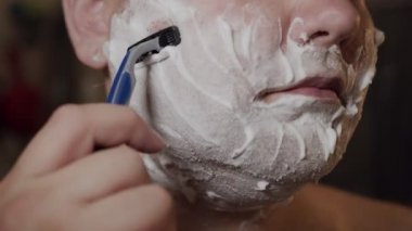 Yetişkin bir adam, Cavid-19 kapanırken sakalını kesmek için bıçak kullanır. Coronavirus salgını, evde kal..