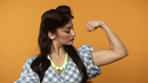 Glimlachende pin up vrouw wijzen met vinger naar biceps — Stockvideo