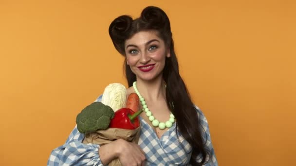 Smiling pin up customer girl holding vegetables in paper bag — Stock Video