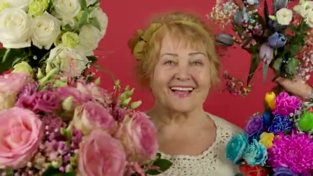 Çiçeklerin yanında gülümseyen heyecanlı yaşlı kadının ön görüntüsü — Stok video