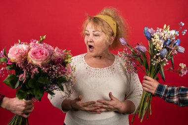 Yaşlı bir kadına aynı anda iki buket güzel çiçek sunulur.