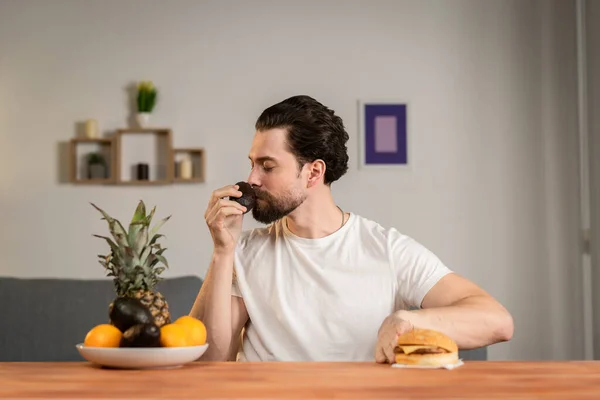 Um jovem senta-se à mesa e fala sobre a utilidade dos frutos, pega neles e mostra abacate. Alimentos saudáveis — Fotografia de Stock