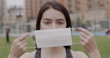 Siyah saçlı bir sporcu kız koşu pistine çıktı. Giderken tıbbi maske takıyor. Virüs ve enfeksiyonlara karşı korunma kavramı.