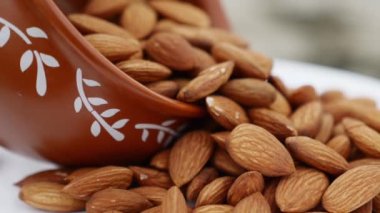 Beyaz arka planda badem. Bir kaseden badem topluyorum. Yakın çekim. Sağlıklı diyet videosu için badem fıstığı