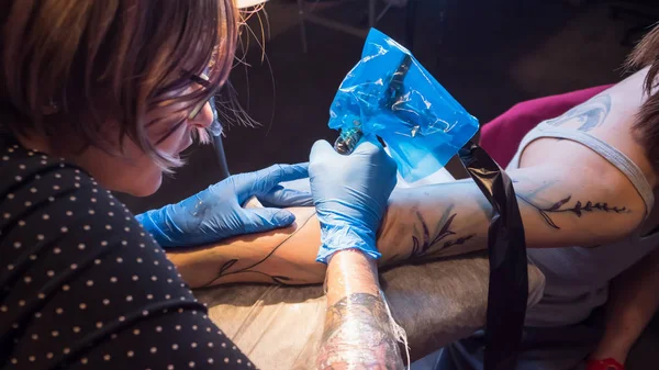 Tattoo artist make tattoo in studio, tattooing on the body.