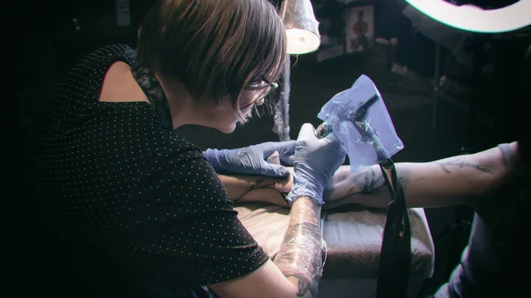 Tattoo artist make tattoo in studio, tattooing on the body.